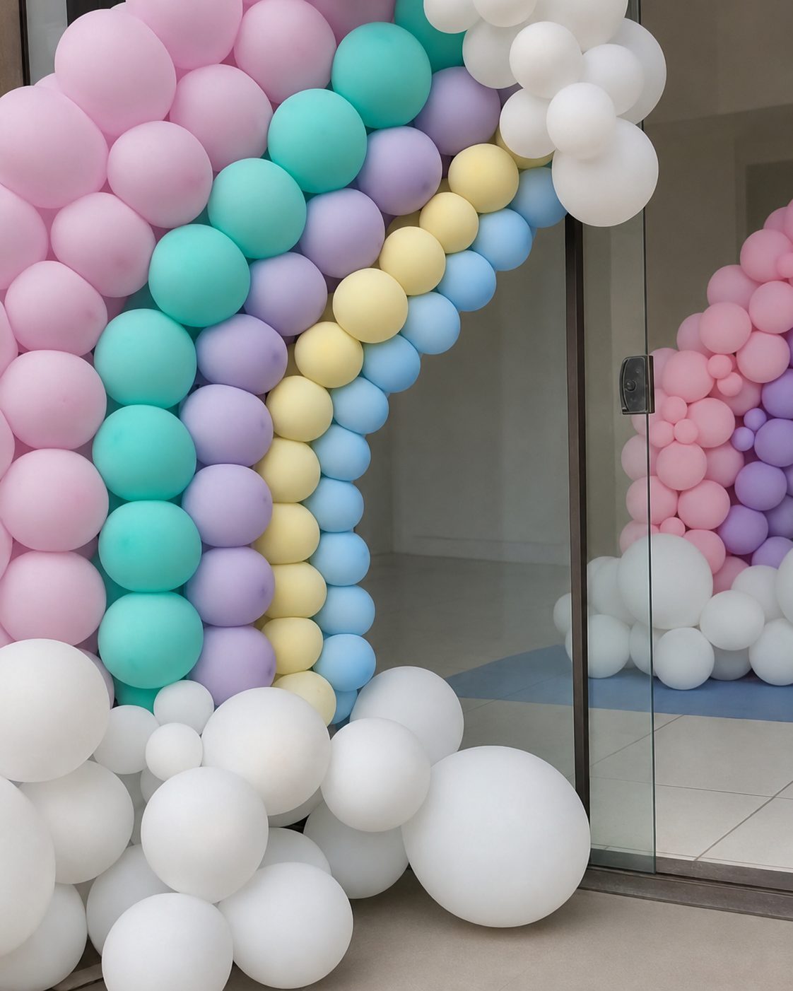 Arco-íris de balões pastel com nuvens brancas montado em evento real